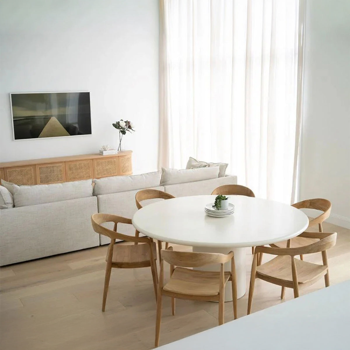 Dining room with a white round table and six wooden chairs arranged around it.
