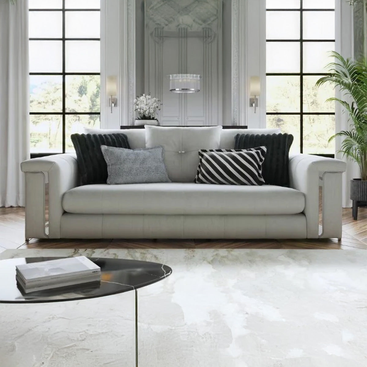 Lifestyle shot of Alcotta luxury cream sofa styled with black and striped pillows in a high-ceiling modern living room.