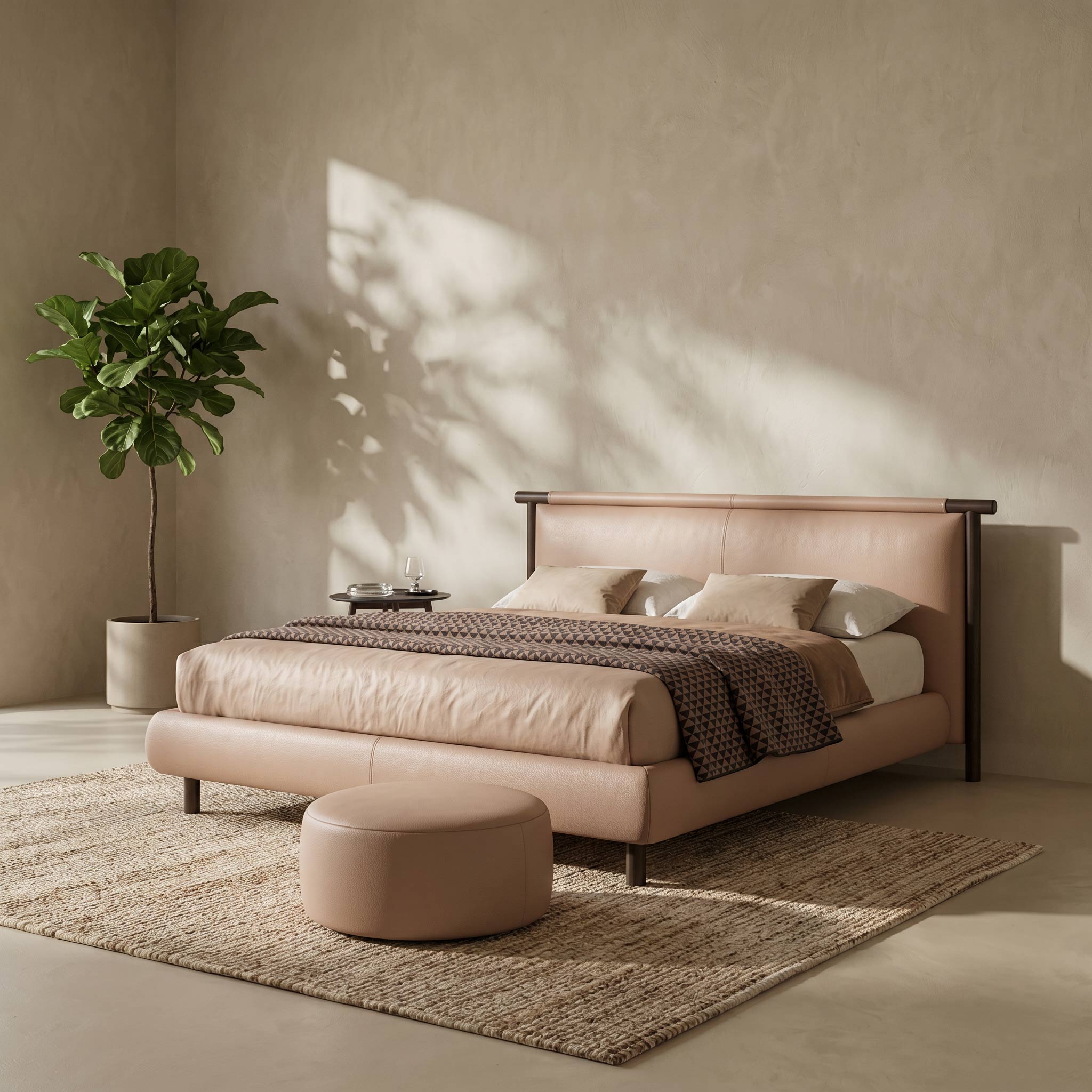 A modern upholstered bed in blush pink leather with dark wood legs, styled in a warm neutral bedroom with a matching ottoman, textured rug, and a potted plant.