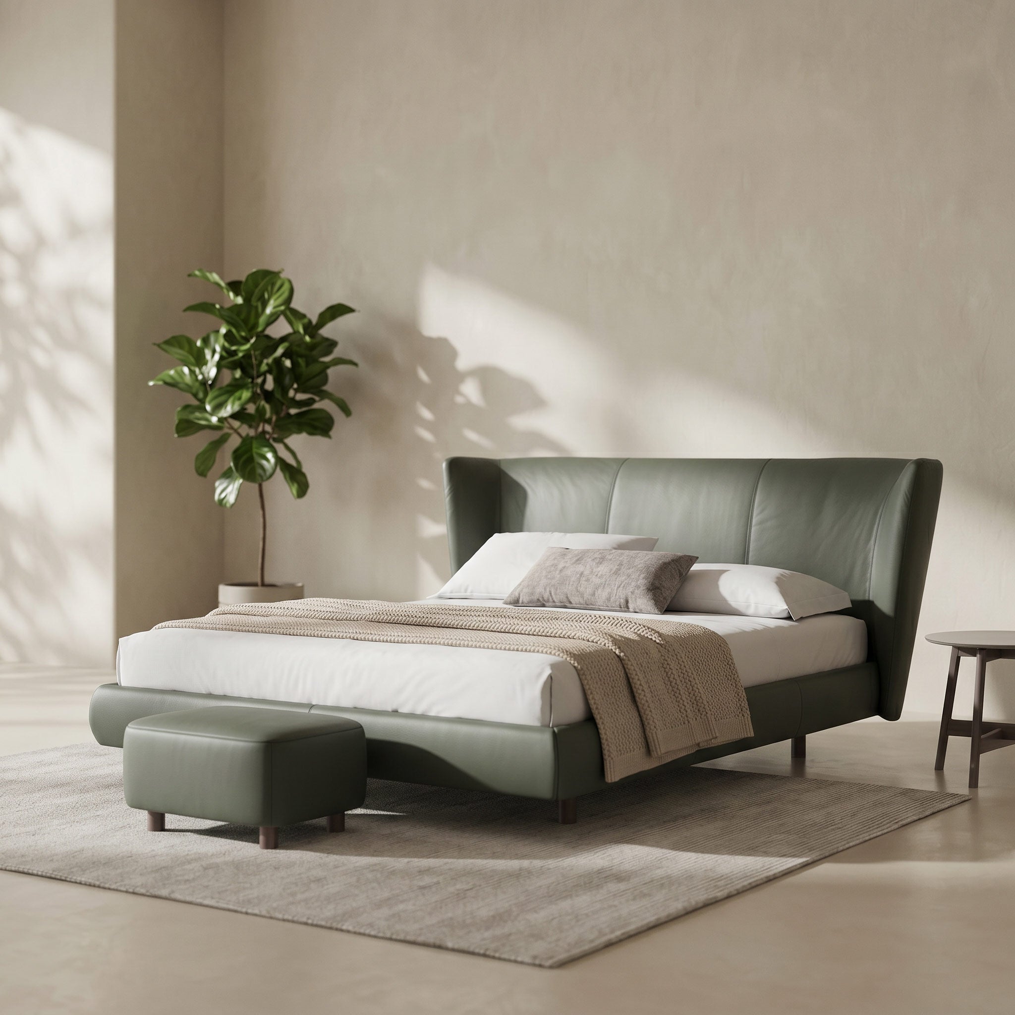 A modern upholstered bed frame in muted sage green, styled in a minimalist bedroom with white bedding, a matching green ottoman, a neutral rug, and a potted plant against a textured beige wall.