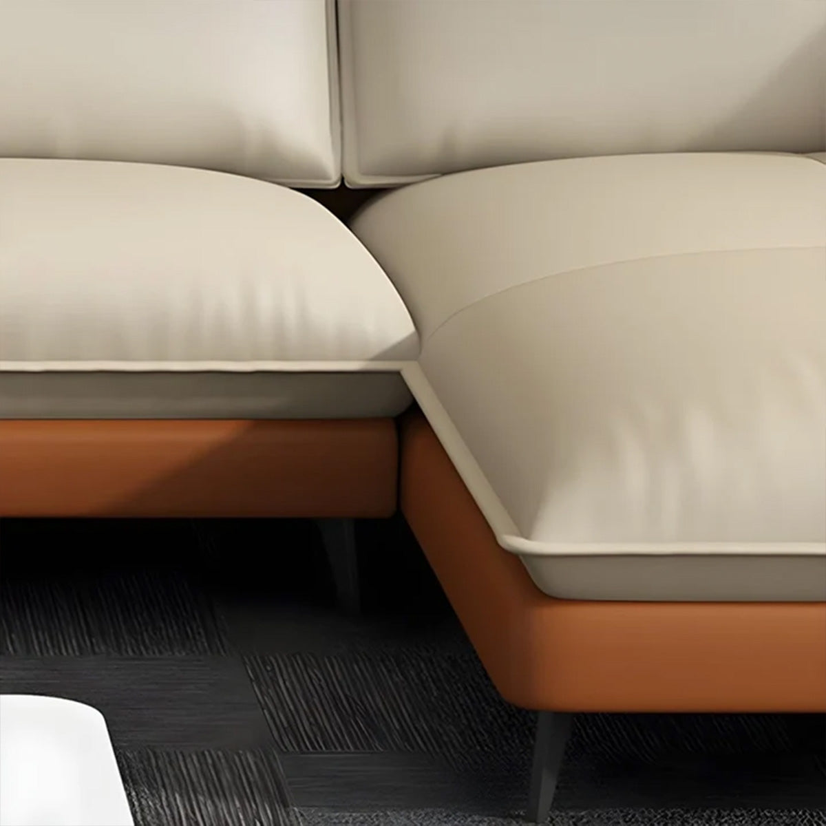Detailed close-up of the corner section of the NOVA sofa. It highlights the fit between two thick, cream-colored seat cushions and the smooth, continuous burnt-orange leather base and sides. Thin black metal legs support the frame.