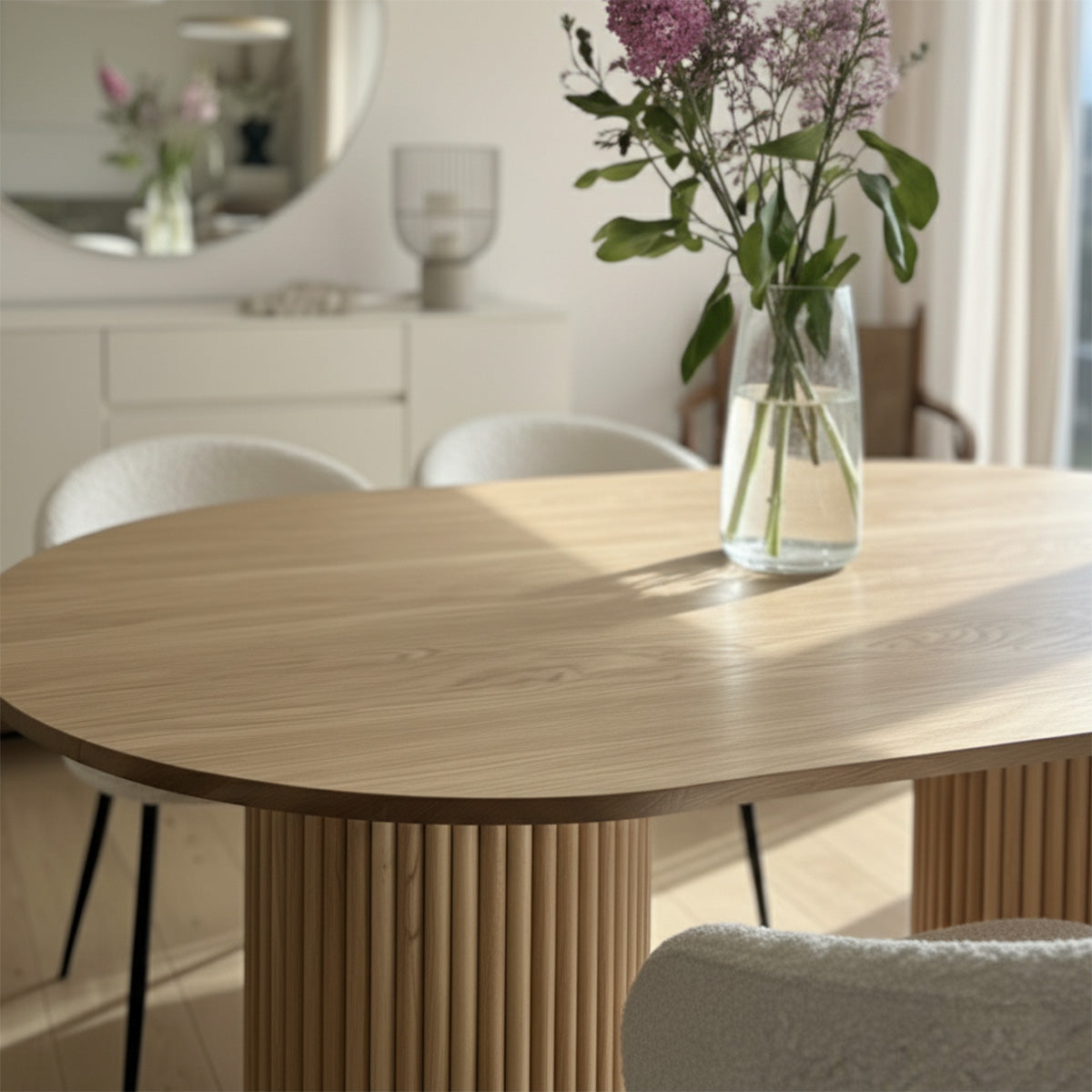 Close-up of natural wood oval dining table surface and slatted wooden pedestal base.