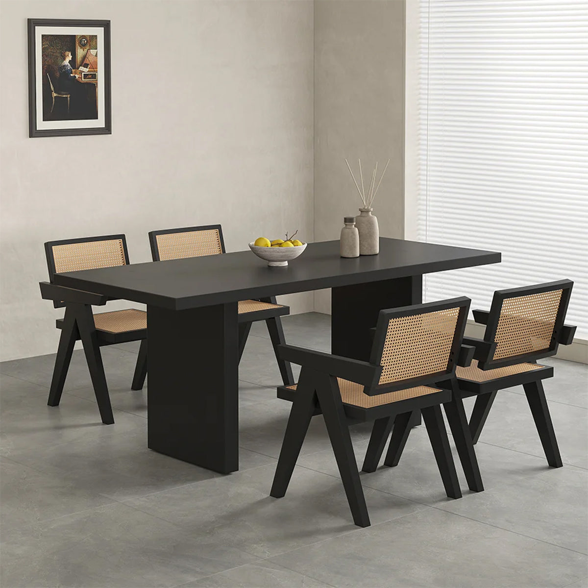 Modern minimalist dining room featuring black dining table and four stylish cane-back chairs, decorated with fruit bowl and vases.