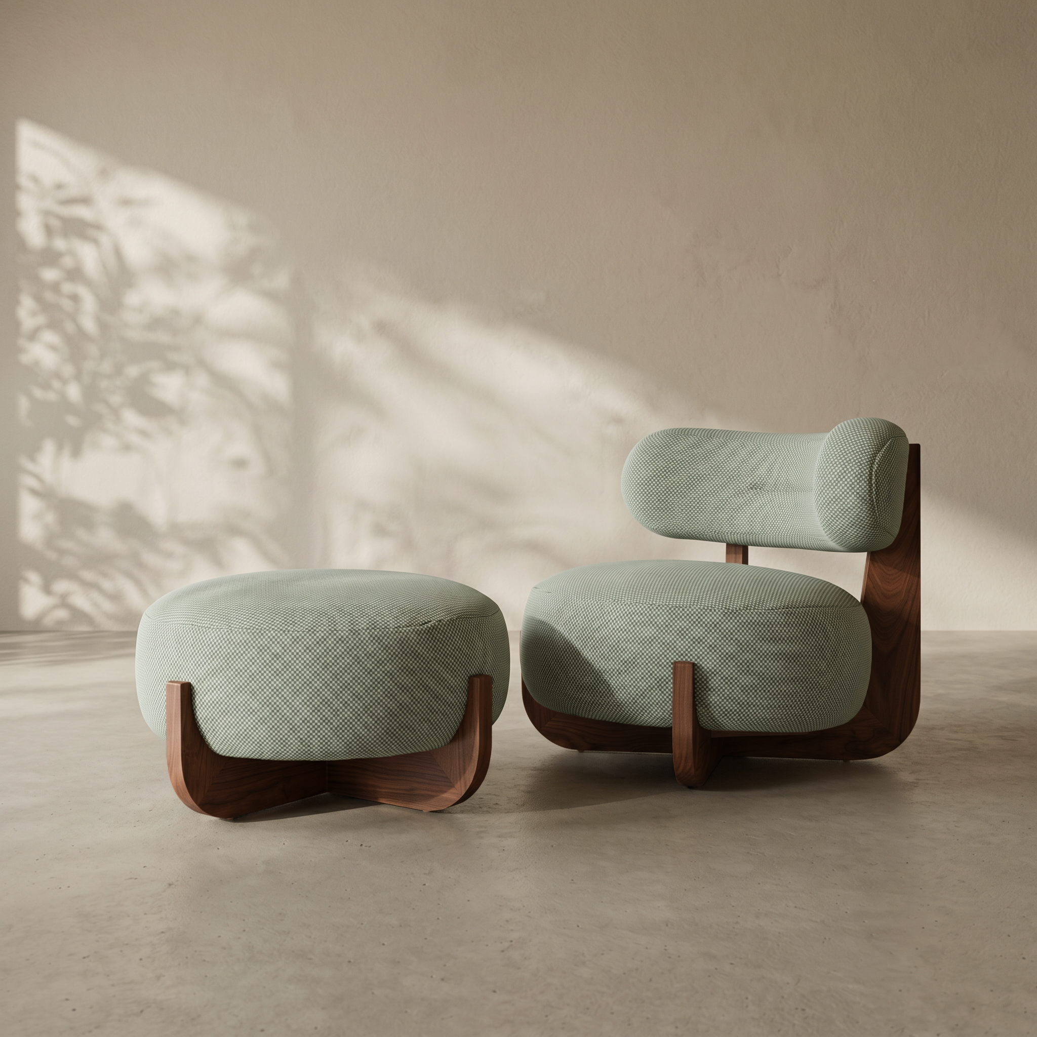 A modern lounge chair with a matching ottoman in a minimalist room. The furniture features textured sage green fabric upholstery and sculptural dark wood bases, set against a warm beige wall with soft leaf shadows.