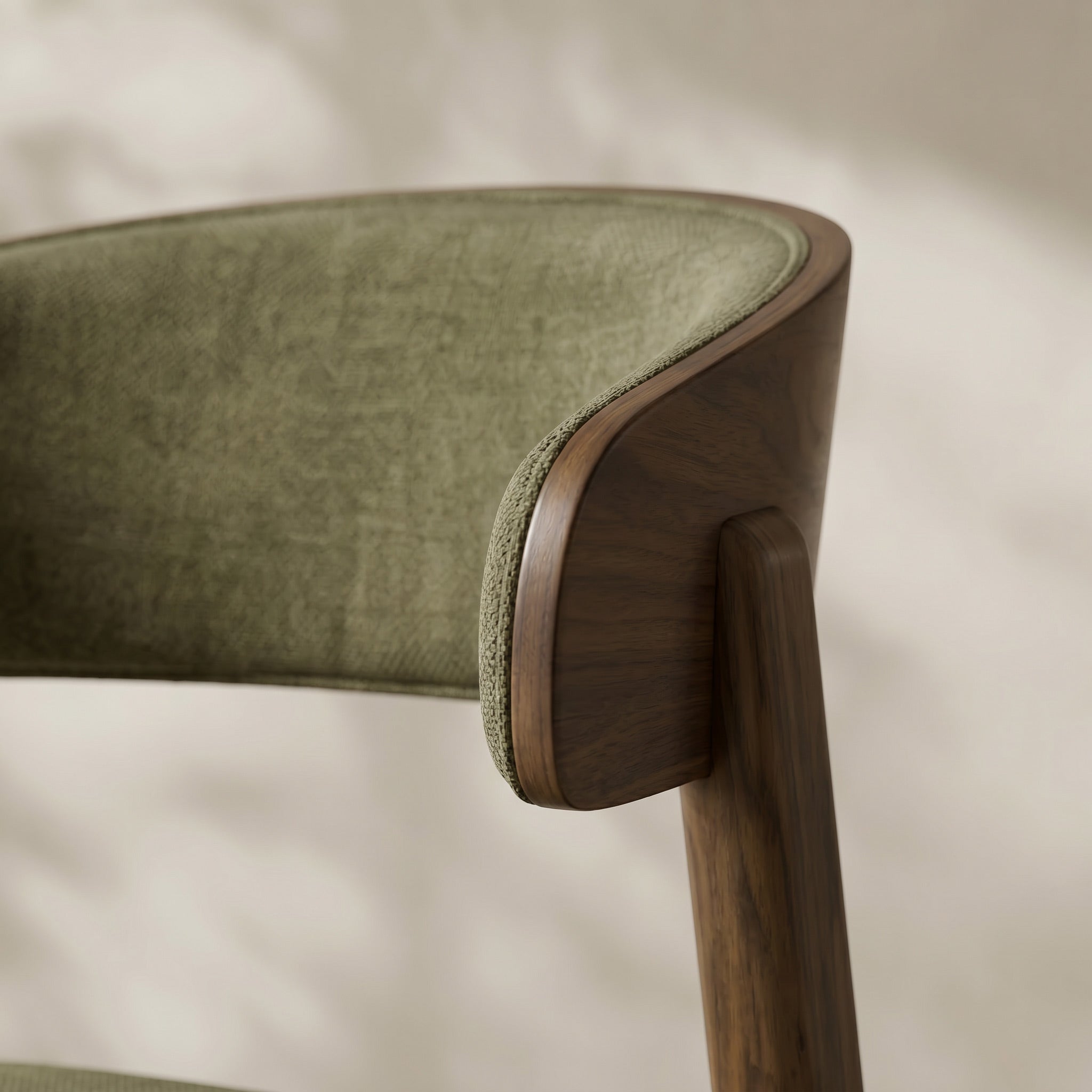 Close-up of a modern chair corner showing olive green upholstered seat and back with a curved dark walnut wood frame and leg.