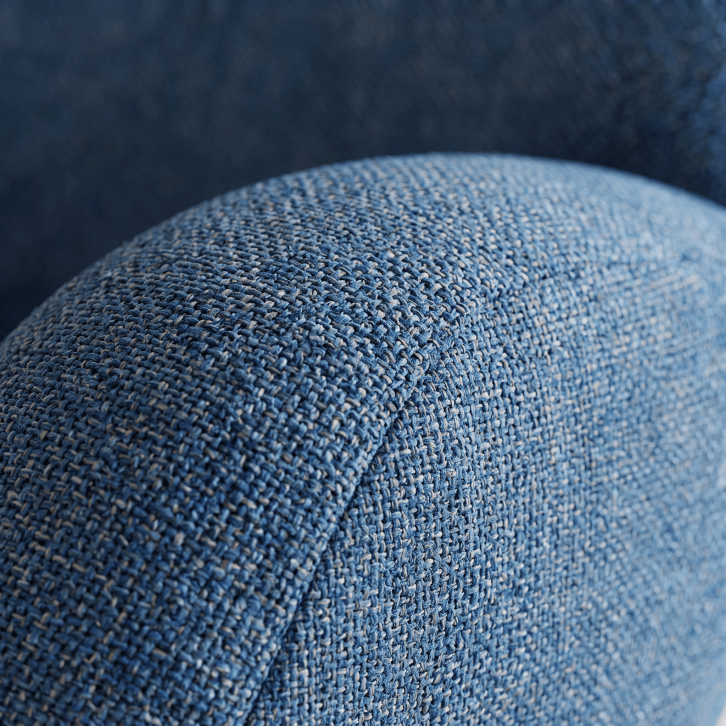 Close-up of a blue woven fabric upholstery surface with visible texture and stitching.