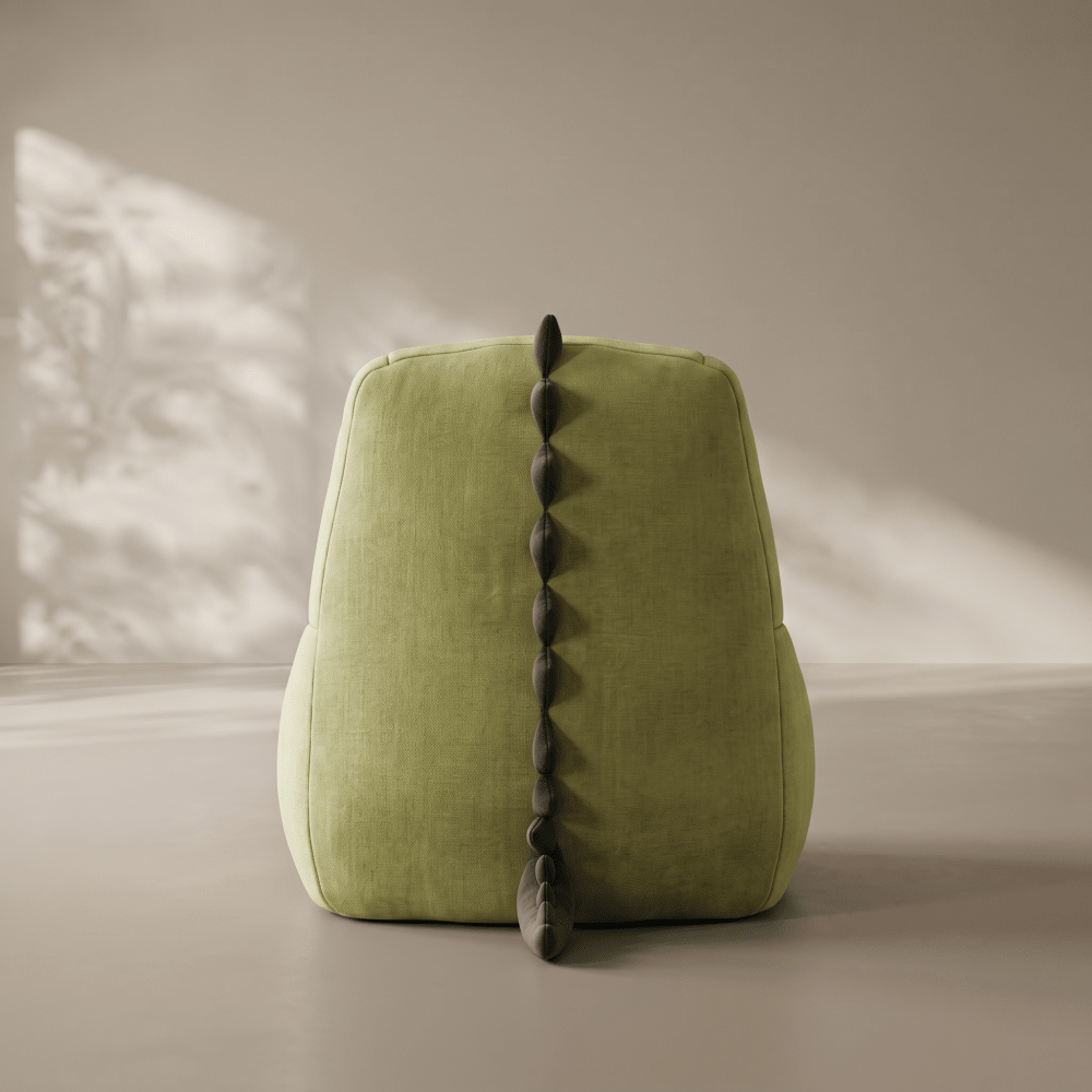 A green dinosaur-style chair or pouf with a dark gray spiked tail detail, photographed in a minimalist studio setting with soft shadow overlays.