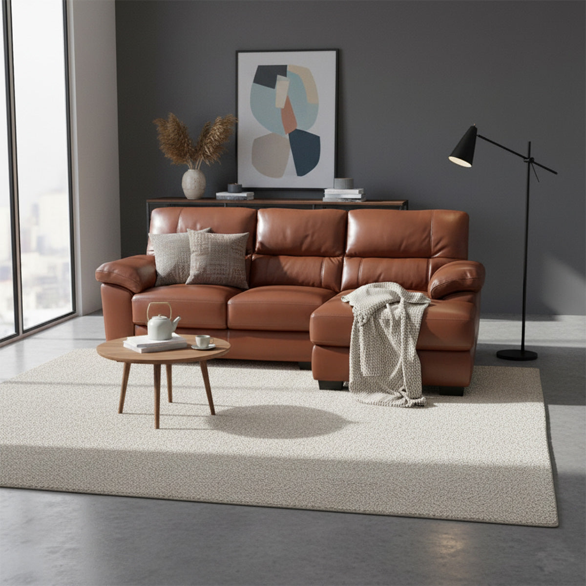 A smaller brown leather 2-seater sofa with a left-hand side (LHS) chaise lounge in a room with a dark accent wall. The sofa is styled with throw pillows and a blanket, facing a low wooden coffee table.