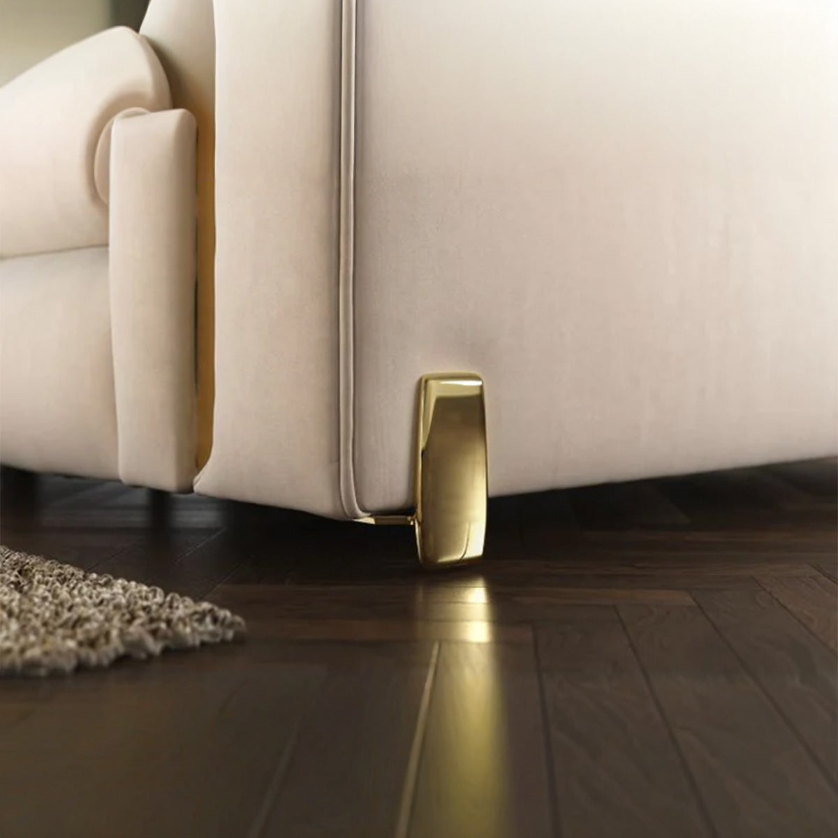 Macro shot of Alcotta sofa gold metal leg showing modern curved design and high-quality finish on dark wood flooring.