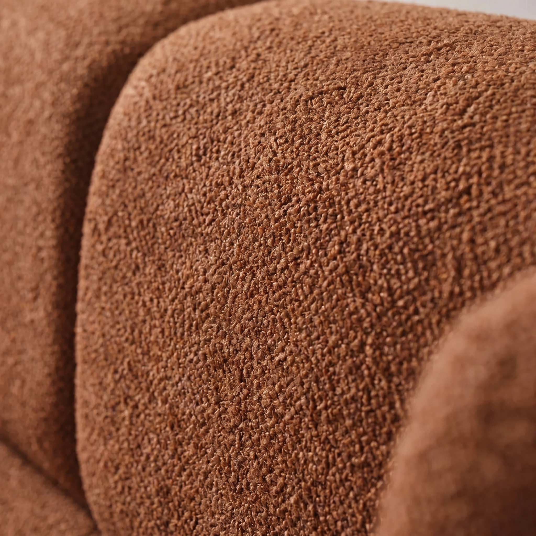 Close-up of a textured brown bouclé fabric upholstery surface with soft rounded contours and no visible product outline or environment.