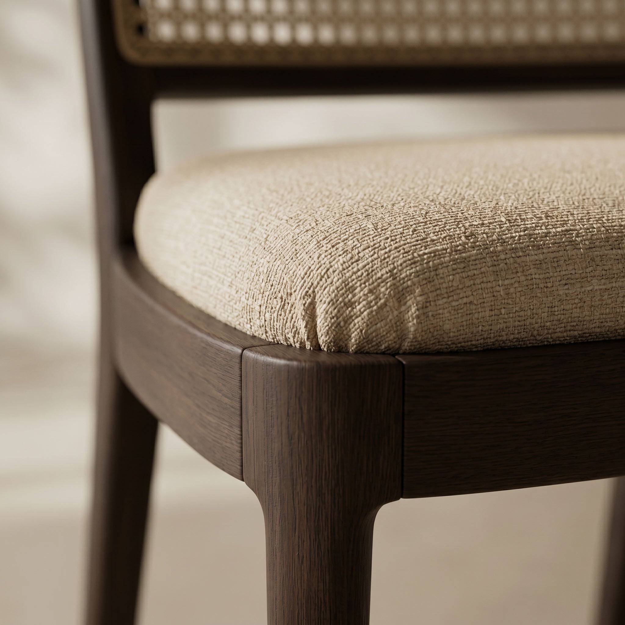 Close-up of a dining chair with a dark brown wooden frame and a textured beige upholstered seat cushion.