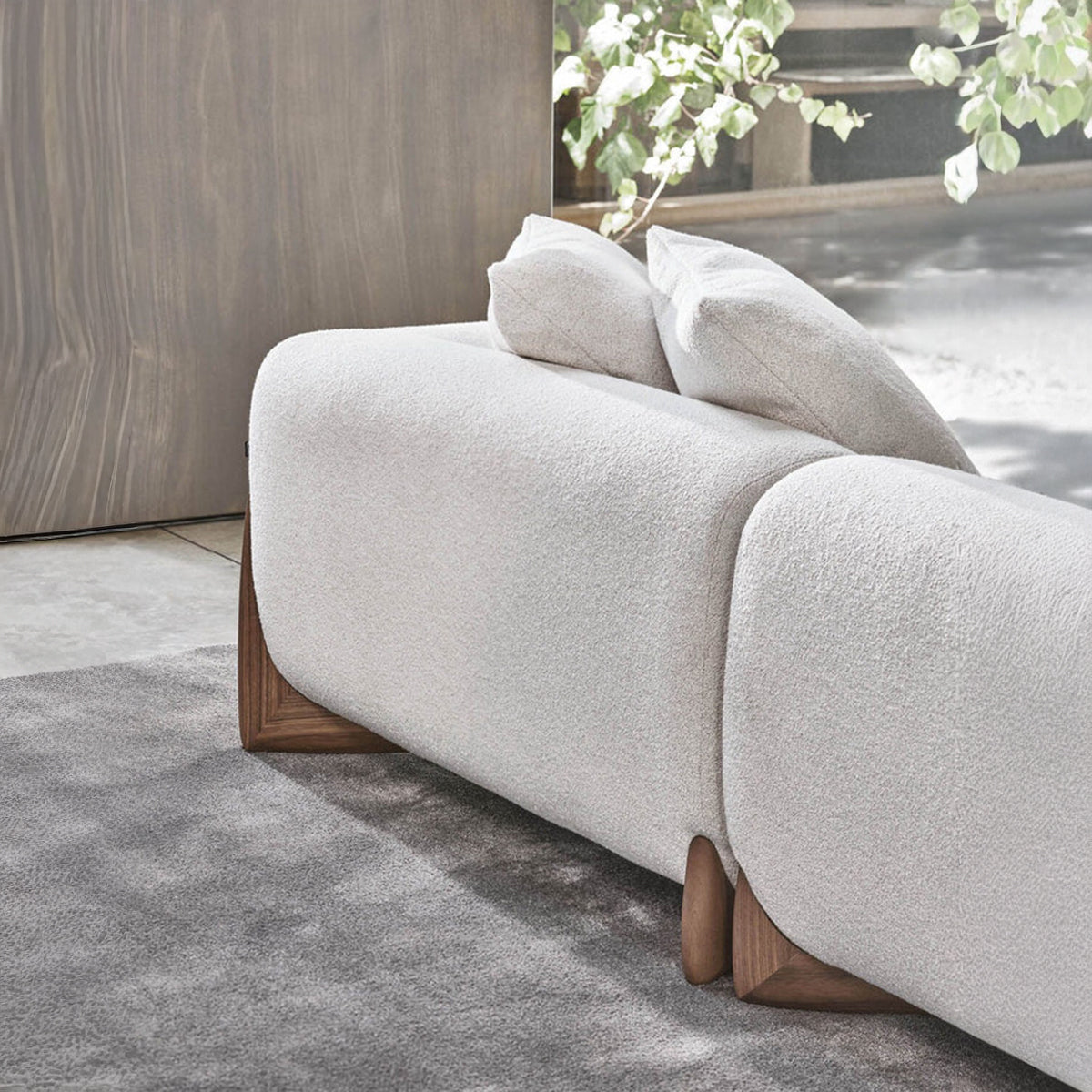 A close-up view of the back of the sofa, highlighting the seam where two sections meet and the curved dark wood foot base.