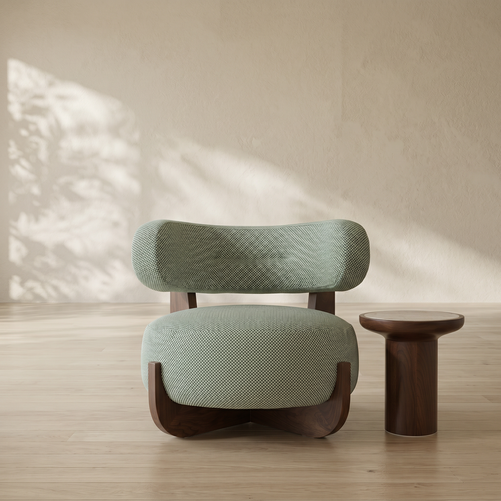 A modern lounge chair with textured sage green fabric and dark wood legs, shown next to a matching dark wood side table in a sunlit room with a textured beige wall.