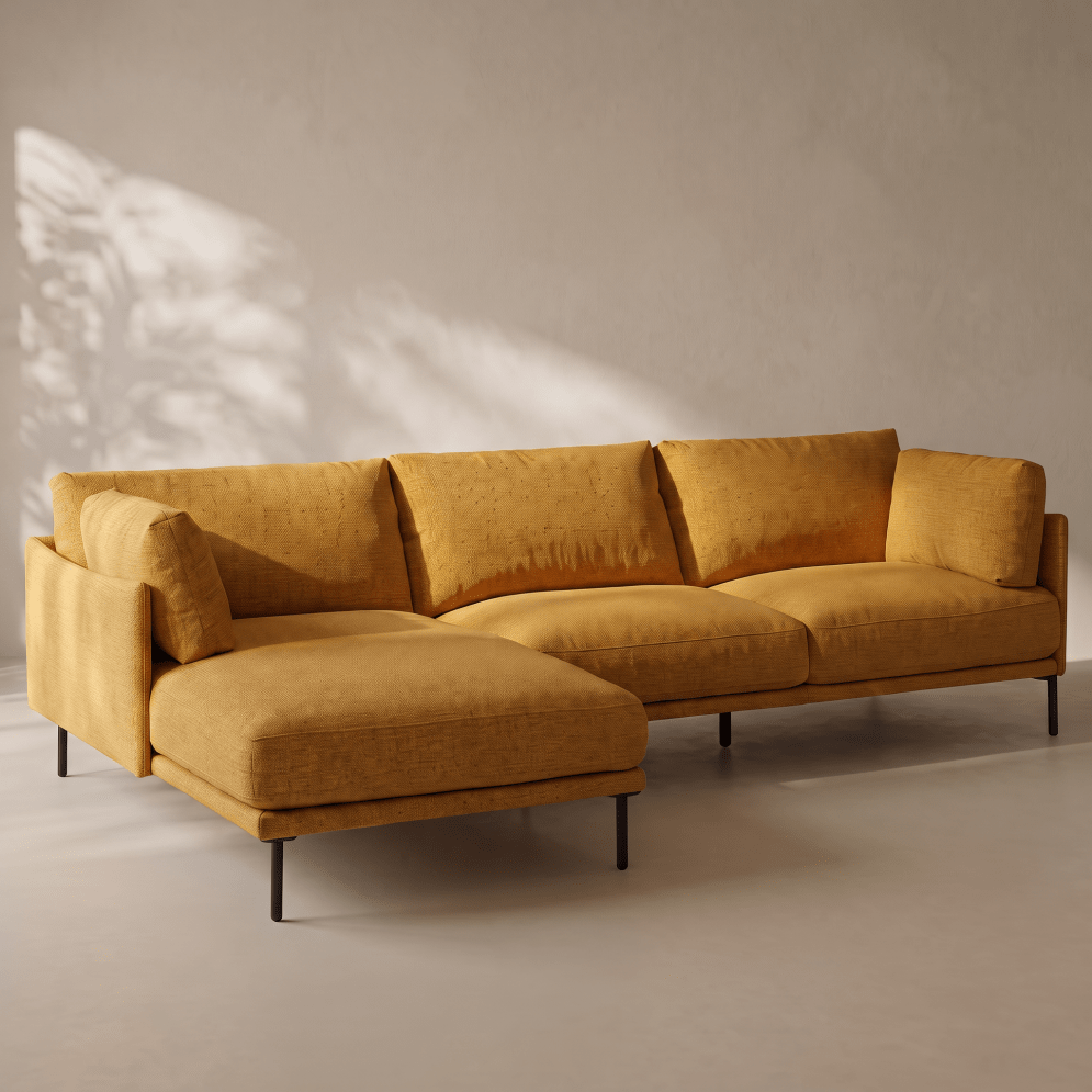 A modern mustard yellow fabric sectional sofa with a chaise lounge, set against a neutral beige wall with soft leaf shadows.