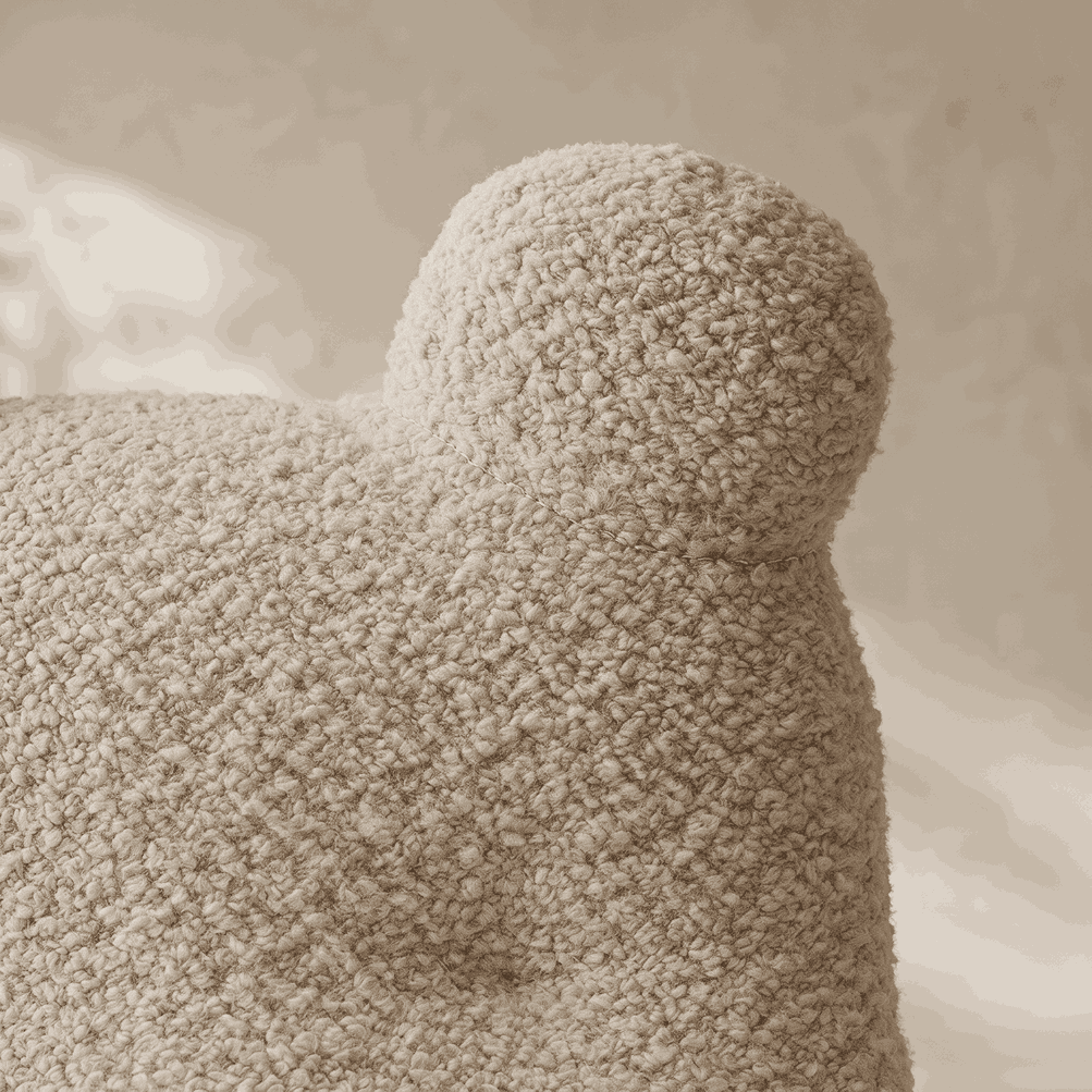 Close-up of a textured, chunky bouclé throw pillow in a warm cream or oatmeal beige color, showing the soft, looped fabric detail.
