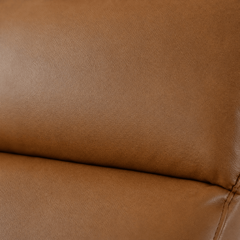 Close-up of a warm tan leather or faux-leather upholstery surface with visible grain texture and a seam line.