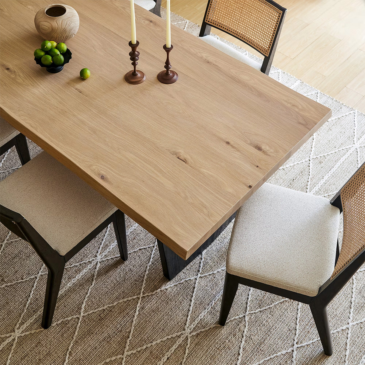 Close-up of Lumea solid wood dining table with natural oak finish and cane chairs