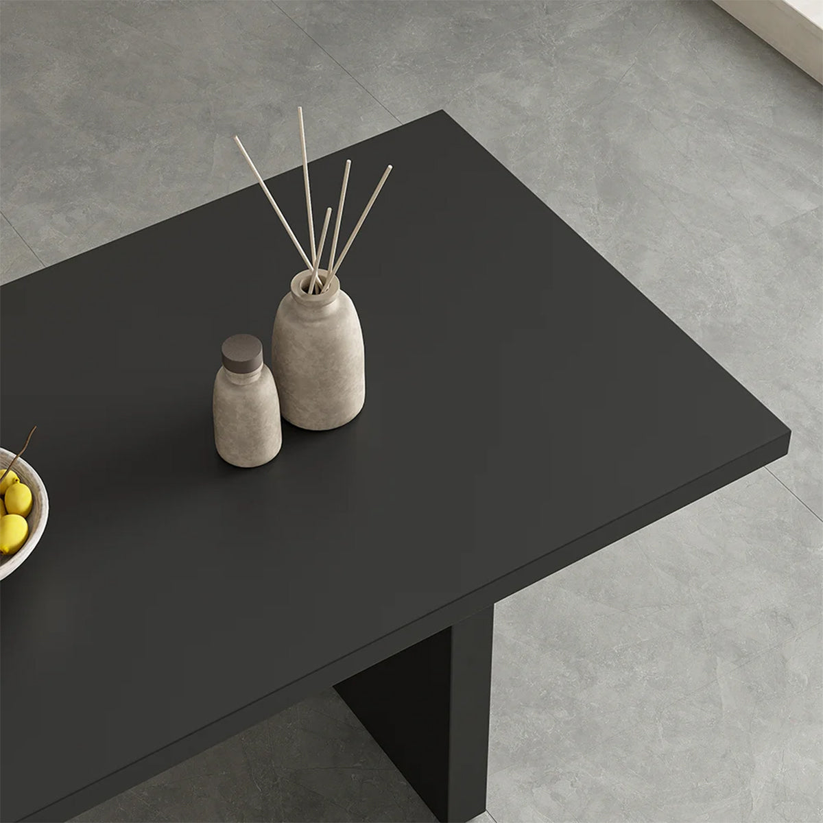 Top-down view of the black dining table surface, adorned with decorative vases and fruit bowl, highlighting texture and accessories.
