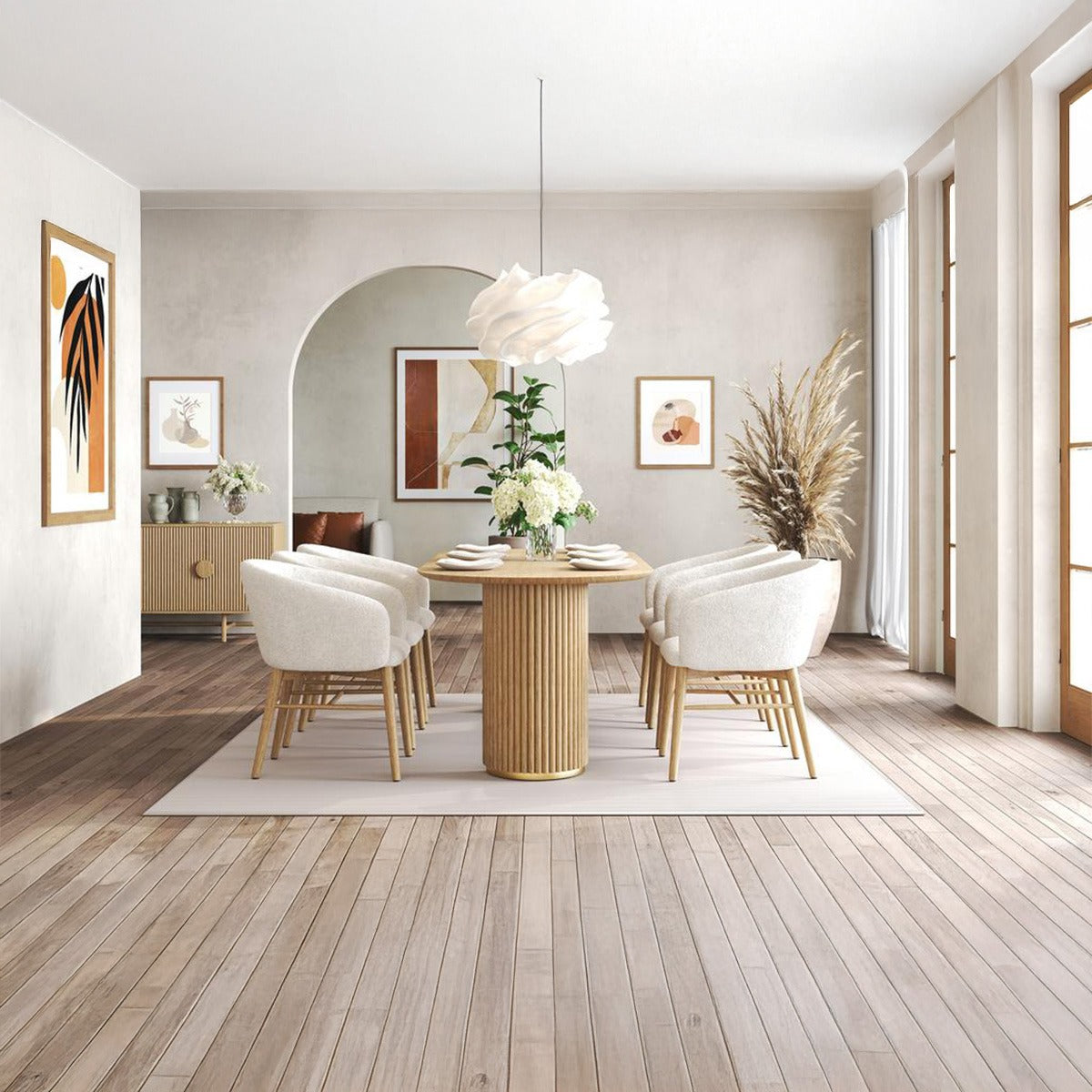 Full shot of the Arco pedestal dining table and boucle chairs in a bohemian/neutral dining room with an archway and abstract art.