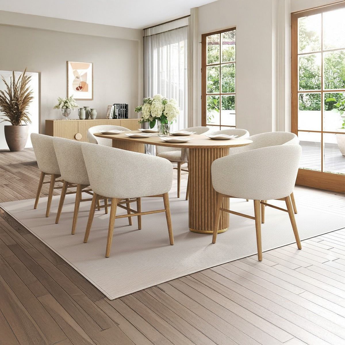 Arco 6-person mid-century modern dining set with oval natural wood fluted pedestal table and six cream boucle upholstered dining armchairs in a bright, natural dining room.