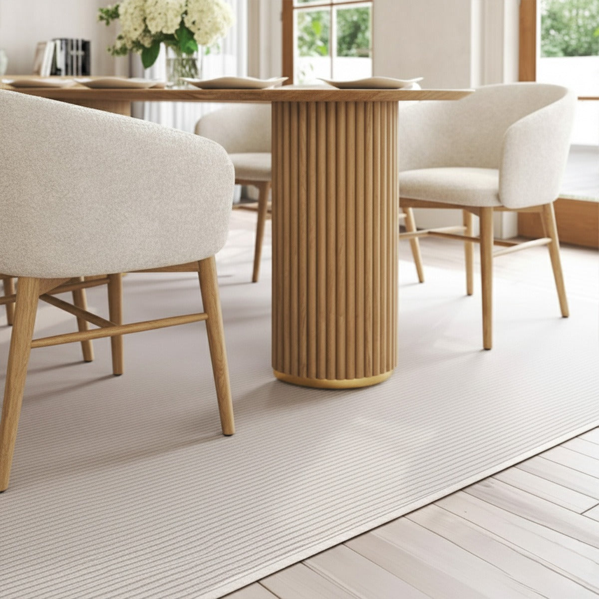 Close-up of the Arco fluted table base and the cream boucle fabric of the dining chair with its light wood frame on a low-pile rug.