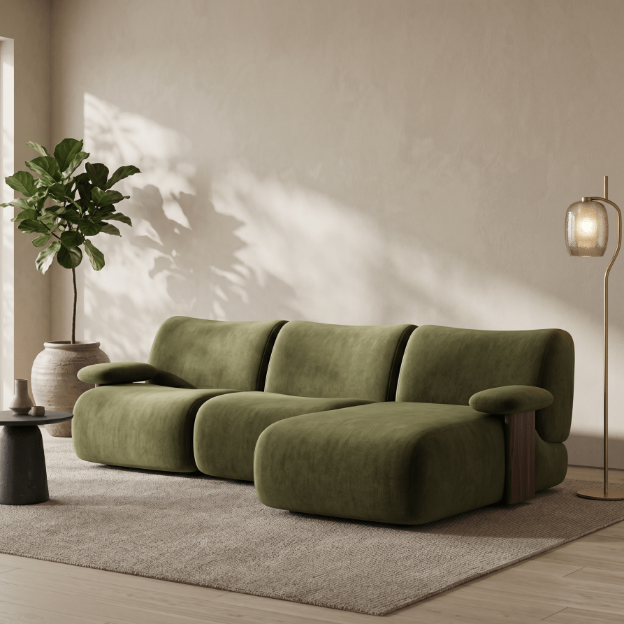 A modern olive green sectional sofa with a low chaise lounge, styled in a minimalist living room with a beige rug, a potted plant, and a floor lamp.