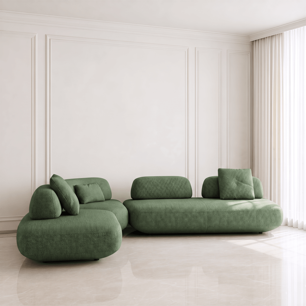 A modern green modular sofa set with rounded, organic shapes and matching cushions, placed in a bright, minimalist room with white paneled walls and light-colored flooring.