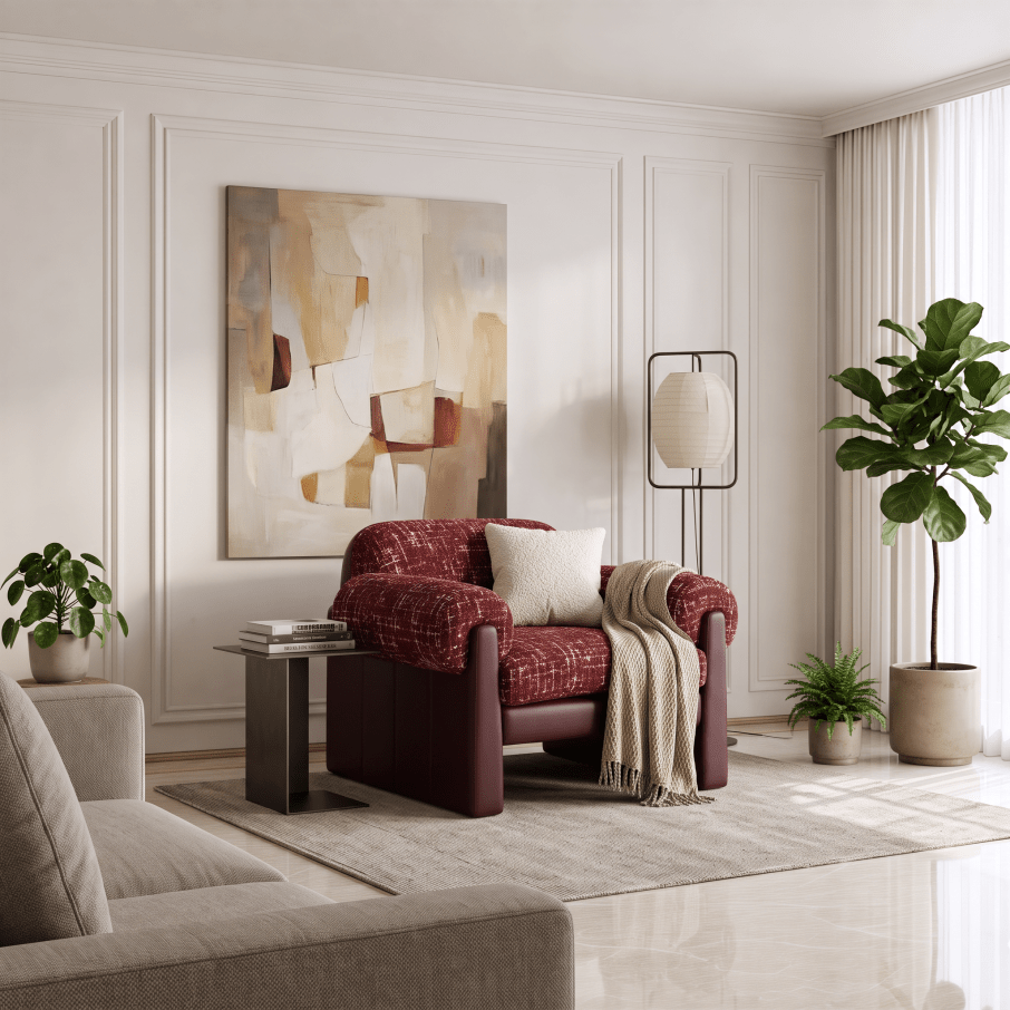 A styled living room interior featuring a red textured armchair as the focal furniture piece, styled with a cream throw pillow, a beige knit throw blanket, a small side table, a floor lamp, and a large abstract painting on the wall.