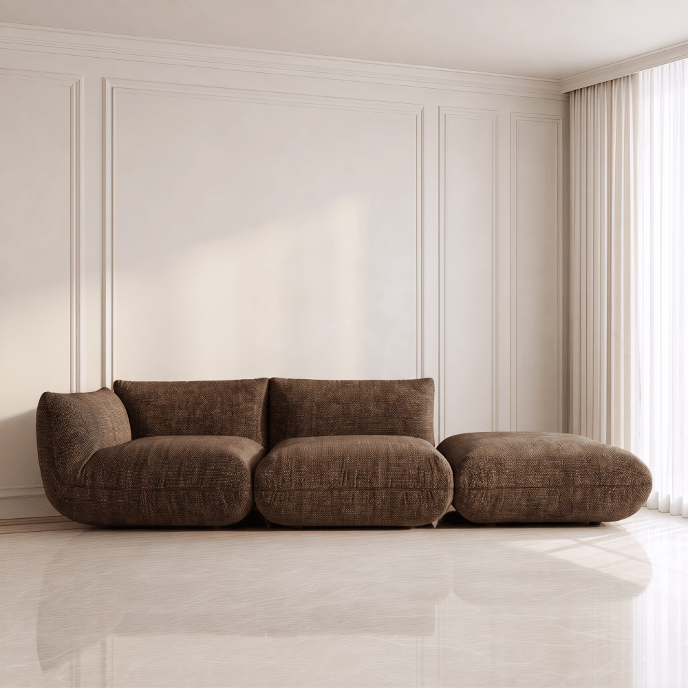 A modern three-seater sofa in a dark brown textured fabric, styled in a minimalist living room with cream paneled walls and a marble floor.