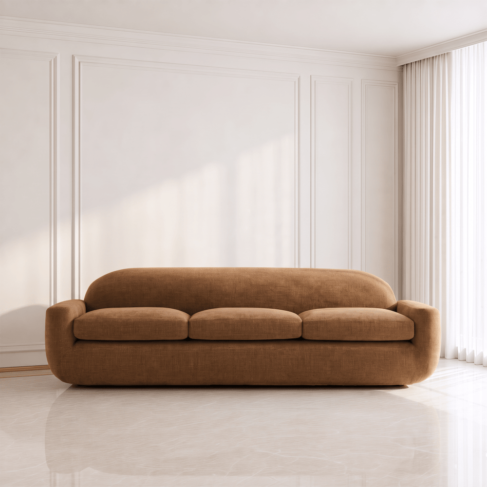A modern three-seat sofa upholstered in warm camel brown fabric, positioned in a minimalist room with white paneled walls and a light marble floor.