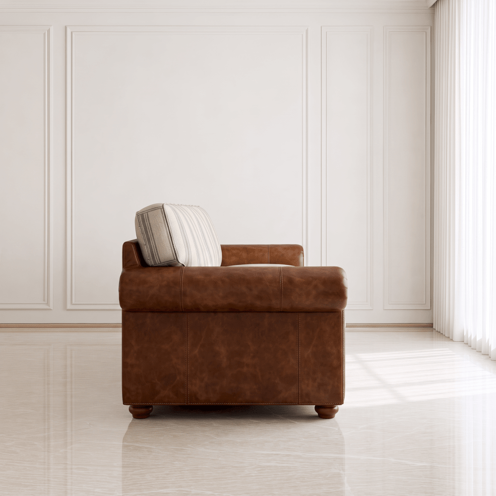 A brown leather storage ottoman chair with a striped accent pillow, set in a bright, modern room with white paneled walls and a light-colored tiled floor.